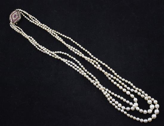 An early 20th century triple strand graduated natural pearl necklace with cabochon ruby and old cut diamond set oval clasp, 21in.